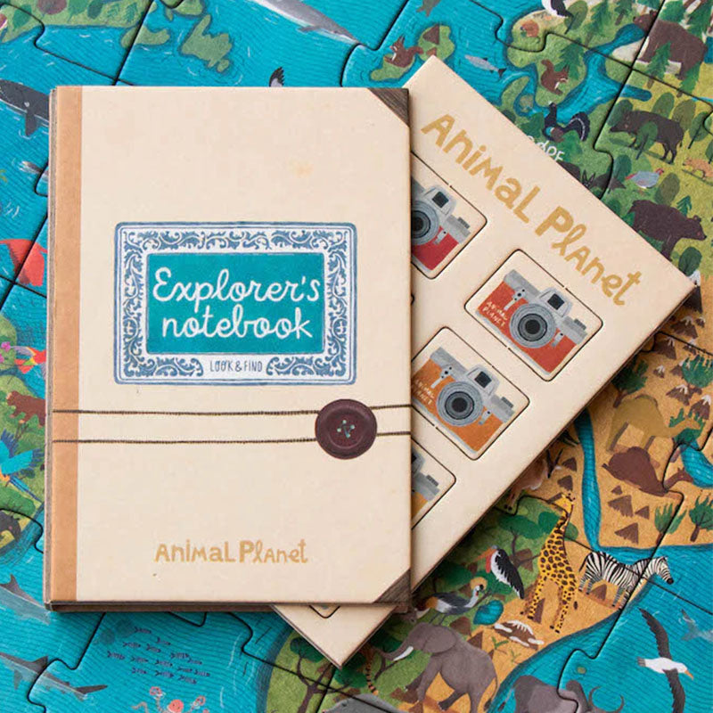 Kleines Notizbuch „Explorer’s Notebook“ und Begleitheft liegen auf dem zusammengesetzten Puzzle mit Tiermotiven.