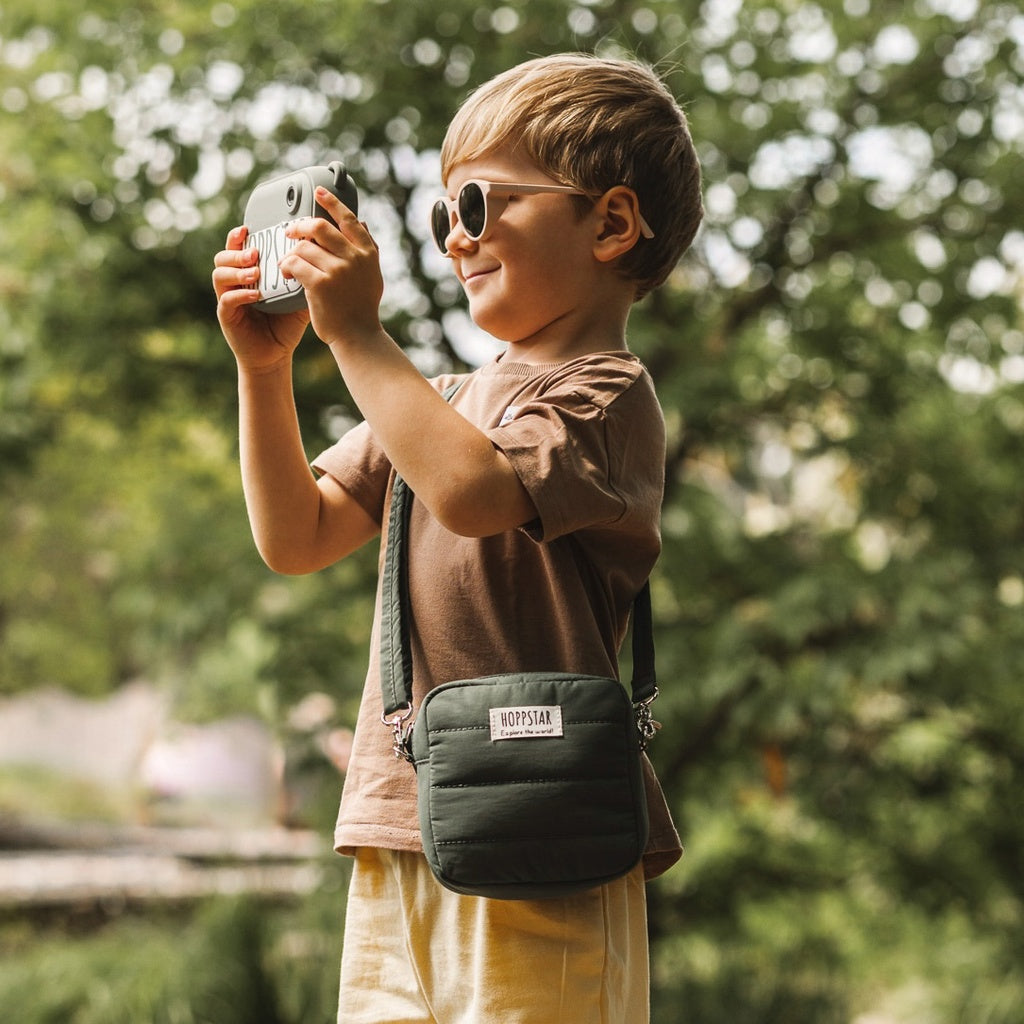 Kind entdeckt den Wald mit der Hoppstar Midi Bag Laurel – weiche, strapazierfähige Kameratasche für Kinder, exklusiv im Waldpark Hochreiter Shop.