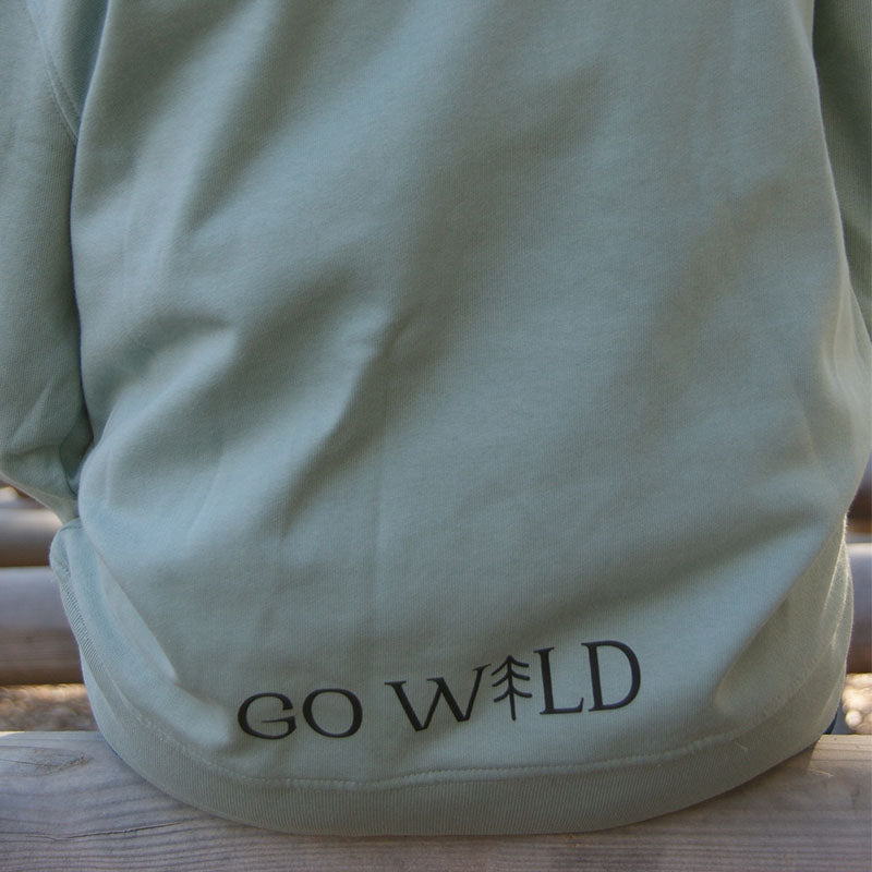 Detailaufnahme des aloegrünen Kinderhoodies aus Bio-Baumwolle, zeigt feine Stoffstruktur und hochwertige Verarbeitung im natürlichen Licht.