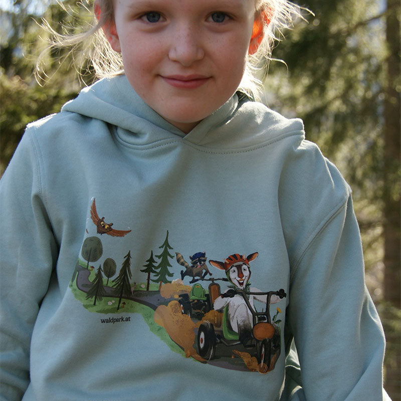 Kind spielt im Wald und trägt den aloegrünen Bio-Baumwollhoody, nachhaltige Mode für aktive Tage in der Natur