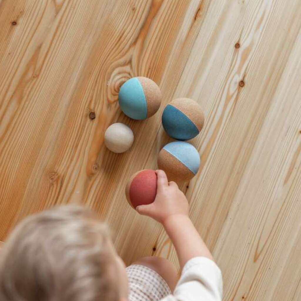 Kind greift nach Boccia Kugel aus Kork