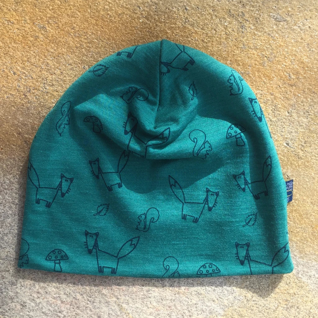 Nahaufnahme der smaragdfarbenen Kinderhaube aus Merinowolle und Seide mit Fuchs-Motiv, zeigt natürliche Stoffstruktur und sorgfältige Handarbeit