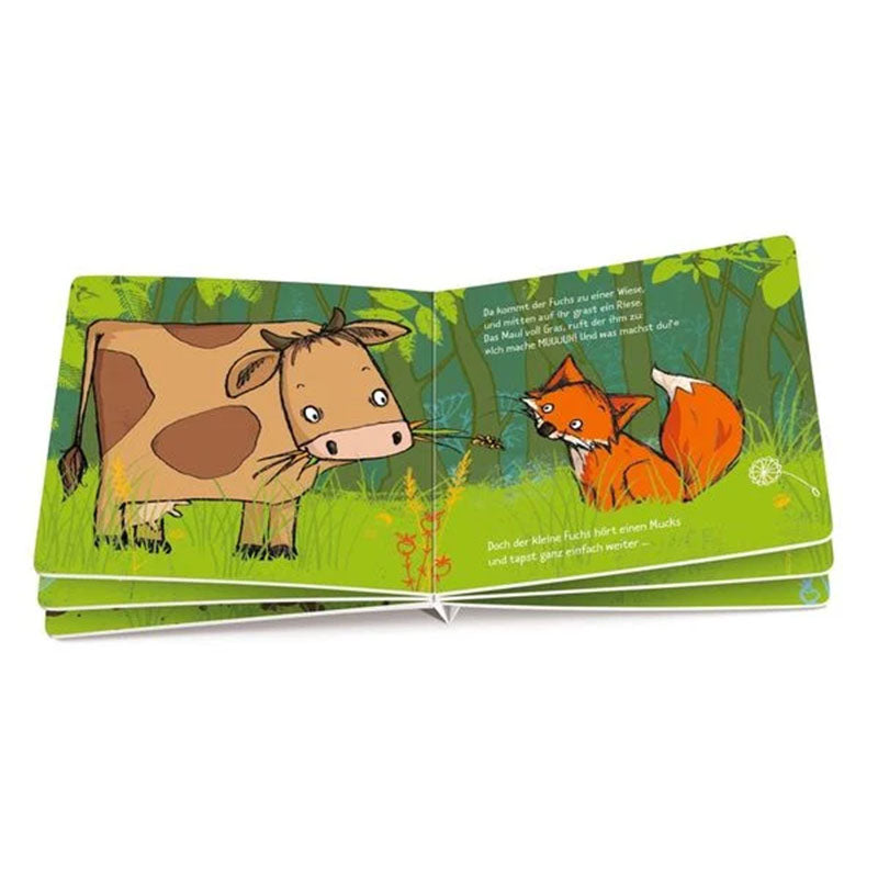Geöffnetes Buch: Fuchs begegnet einer Kuh auf einer grünen Wiese