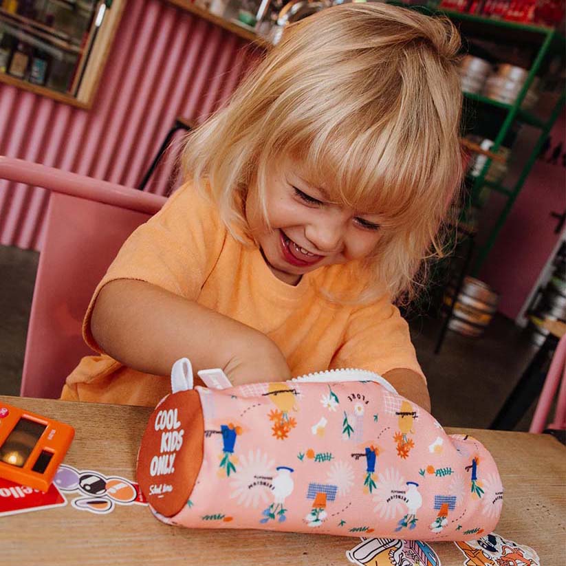 Kind spielt am Tisch mit Federmappe in der Farbe Flore