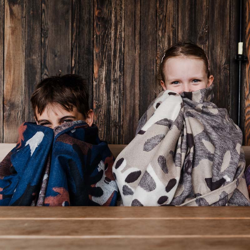 Zwei Kinder verstecken sich hinter zwei Kuscheldecken