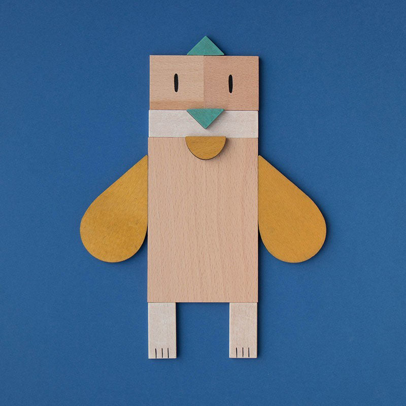 Vogel aus Holzformen mit gelben Flügeln und grünem Schnabel auf blauem Hintergrund.