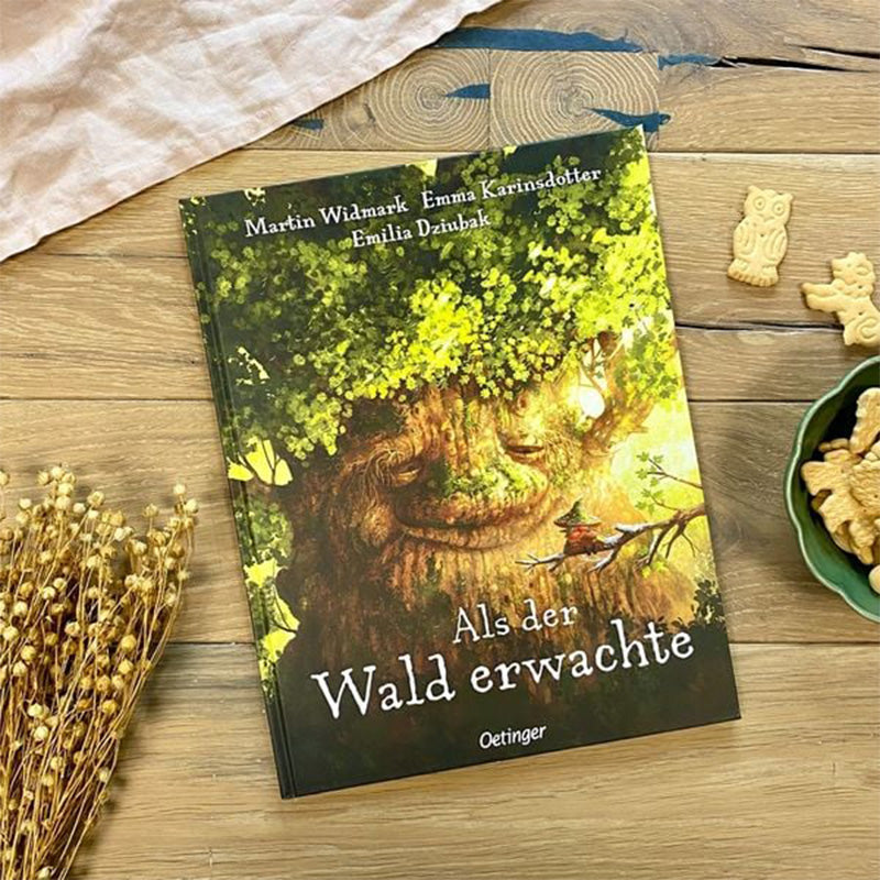 Kinderbuch Als der Wald erwachte von Martin Widmark, Emma Karinsdotter und Emilia Dziubak. Auf dem Cover ist ein riesiger Baum mit Gesicht abgebildet, der freundlich schaut, während ein Kind darunter im Wald sitzt. Verlag: Oetinger.
