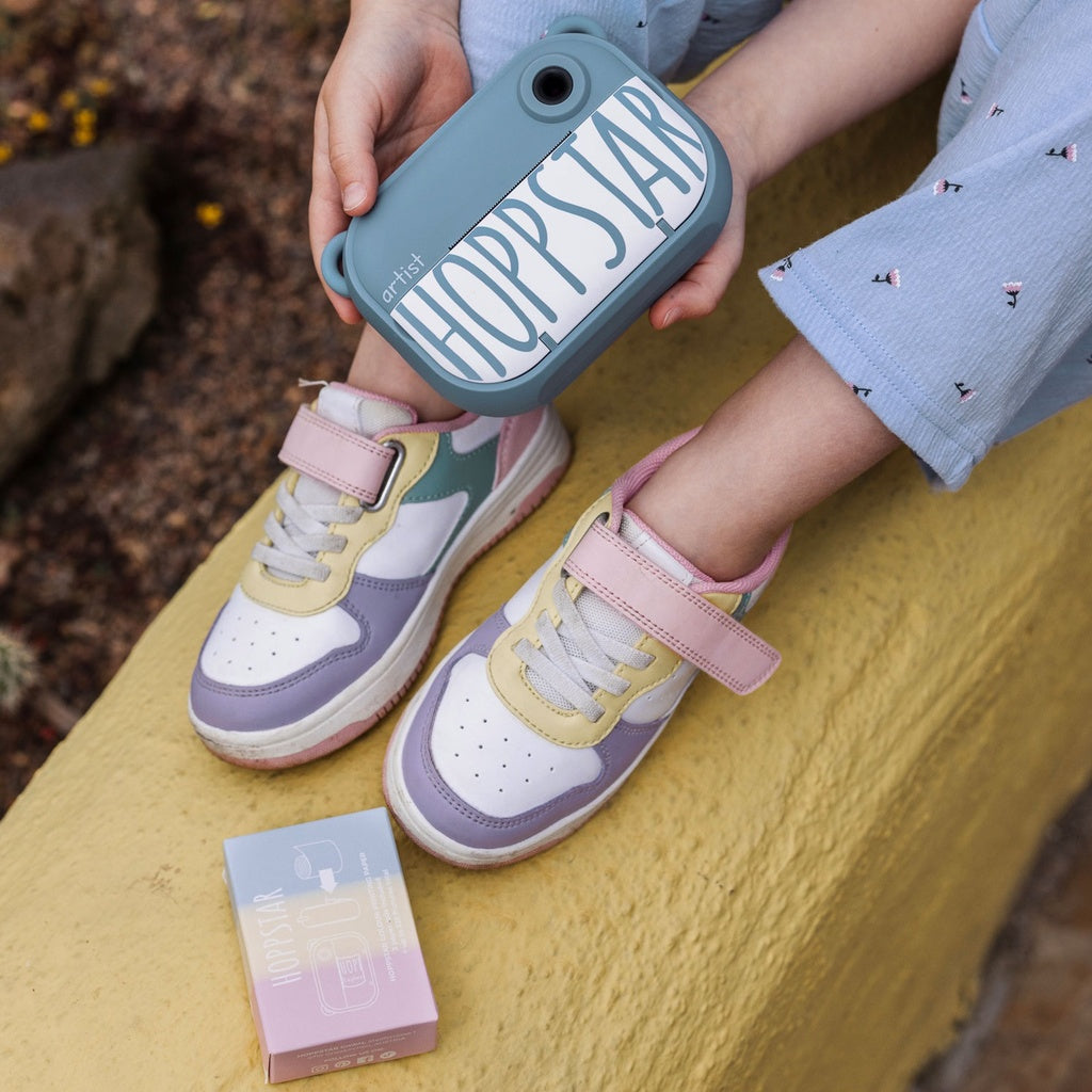 Kind sitzt im freien uns hält die Hoppstar Artist Denim in der Hand