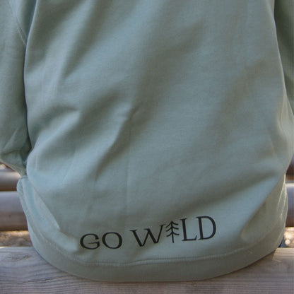 Detailaufnahme des aloegrünen Kinderhoodies aus Bio-Baumwolle, zeigt feine Stoffstruktur und hochwertige Verarbeitung im natürlichen Licht.