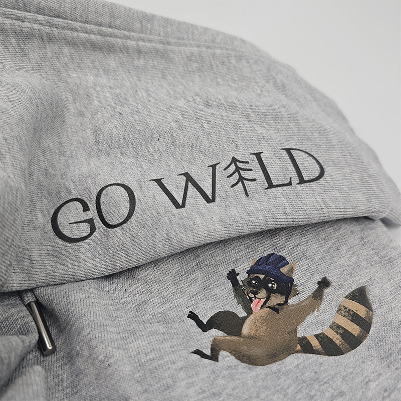 Detailaufnahme des Waschbären-Motivs mit Sturzhelm auf grauer Bio-Baumwollhose, hochwertiger Druck und feine Stoffstruktur, auf weißem Hintergrund.