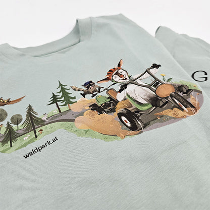 Detailaufnahme des grünen Go Wild Shirts, Vorderseite mit verspieltem Go-Kart-Motiv, zeigt liebevolle Illustrationen von Ziege und Waschbär