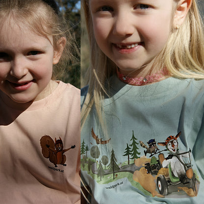 Kind trägt grünes Go Wild T-Shirt im Wald, Vorderseite mit Ziege und Waschbär im Go-Kart, fröhlich beim Spielen und Entdecken