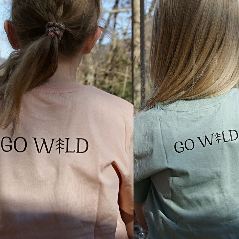 Rückansicht von zwei Kindern, die Waldpark Hochreiter T-shirts mit Go Wild Schriftzug tragen