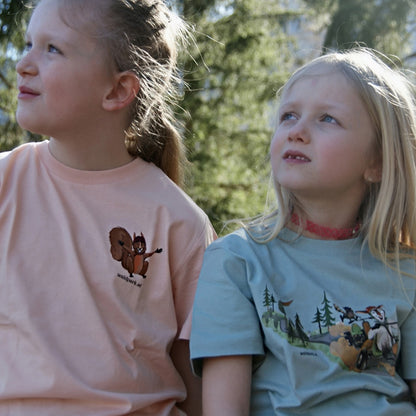 Kind im rosa Go Wild T-Shirt im Wald, Vorderseite sichtbar und zweites Kind im grünen Go Wild T-Shirt robustes Bio-Baumwoll-Shirt für Abenteuer und Ausflüge