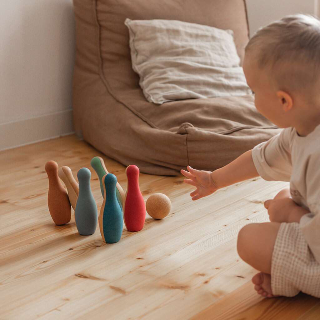 Kind spielt drinnen mit dem Bowling Set aus Kork