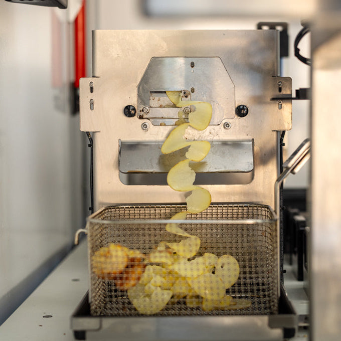 frisch geschnittene Kartoffeln fallen in ein Frittierkörbchen
