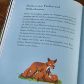 Seite eines Kinderbuchs mit Text über Füchse und Wildschweine, darunter eine Illustration zweier spielender Füchse.
