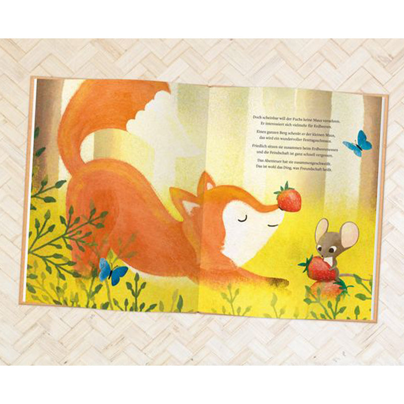 Buchseite: Der Fuchs und die Maus sitzen friedlich zusammen zwischen Pflanzen und essen Erdbeeren, umgeben von blauen Schmetterlingen.