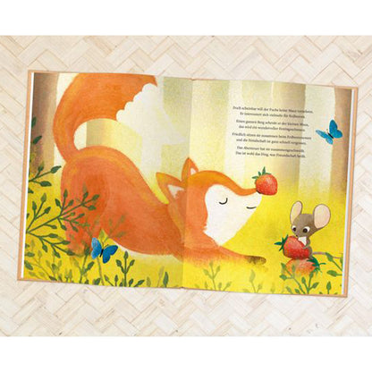 Buchseite: Der Fuchs und die Maus sitzen friedlich zusammen zwischen Pflanzen und essen Erdbeeren, umgeben von blauen Schmetterlingen.