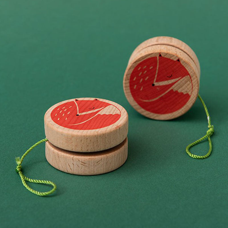 Zwei Holz-Yo-Yos mit grünem Faden, bedruckt mit einem roten schlafenden Fuchs auf grünem Hintergrund.