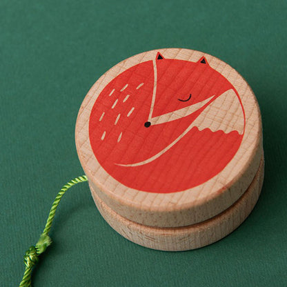 Nahaufnahme eines Holz-Yo-Yos mit grünem Faden, rotes Fuchs-Motiv auf der Oberfläche.