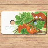 Buchseite mit zwei Eichhörnchen auf einem Ast zwischen grünen Eichenblättern, mit Guckloch.