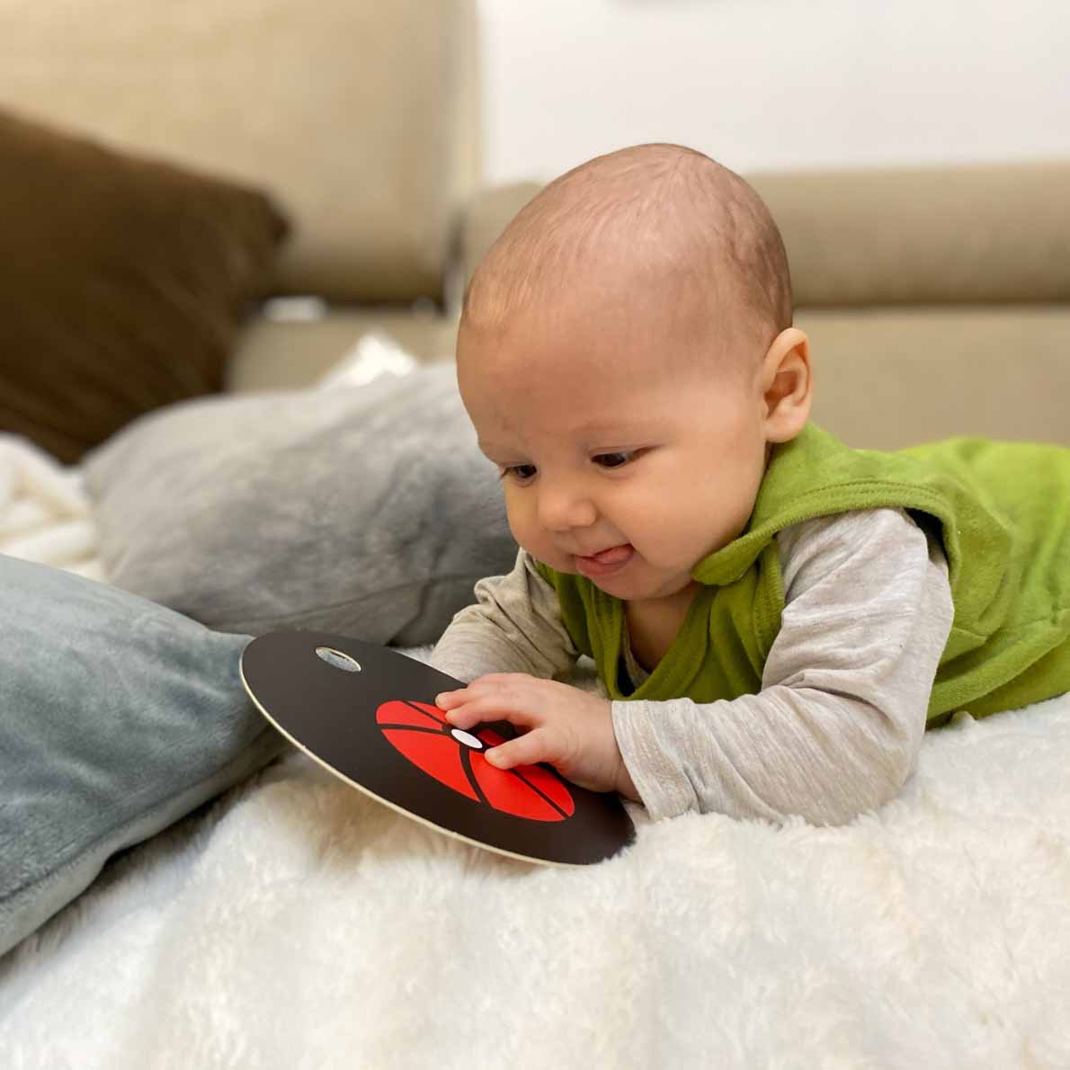 Baby spielt mit Kontrastkarte auf Kuscheldecke