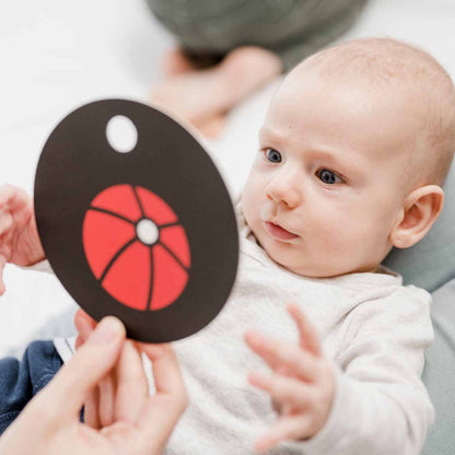 Baby spielt mit Kontrastkarte mit Ball darauf