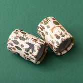 Zwei Kaleidoskope mit Waldmotiven, auf grünem Hintergrund liegend.