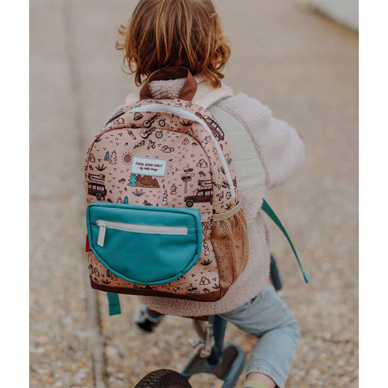 Kind fährt mit einem Laufrad und trägt dabei den beige-grünen Rucksack mit Outdoor-Muster.