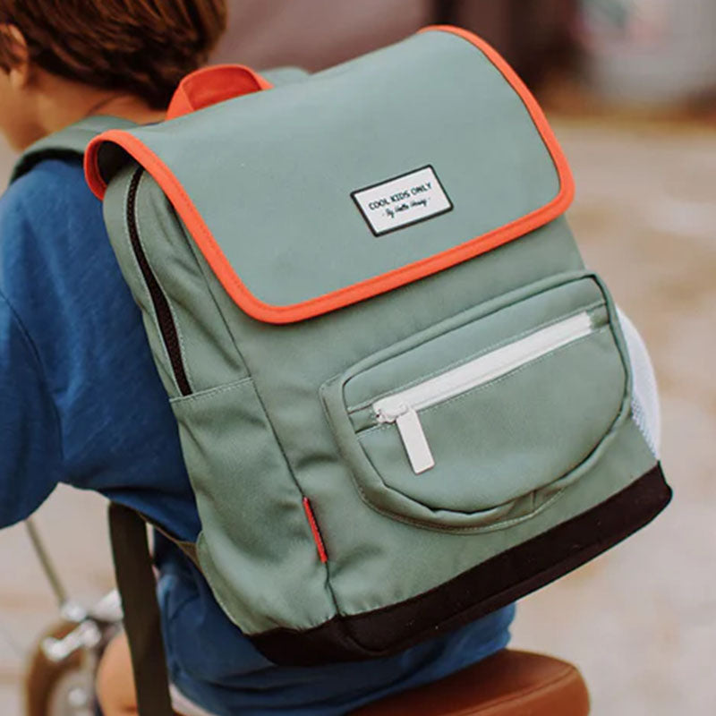 Kind trägt den grünen Rucksack mit roter Einfassung und weißem Reißverschluss beim Fahrradfahren.