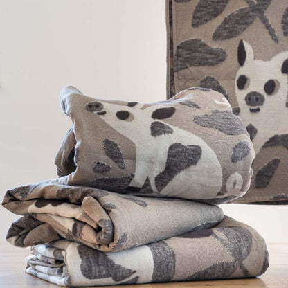 Drei Schweinderl Kuscheldecken liegen gestapelt übereinander, im Hintergrund hängt noch eine weitere Kuscheldecke