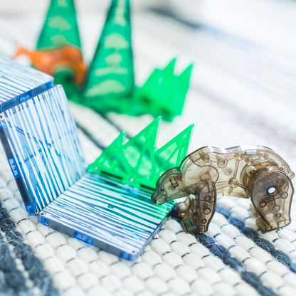 Nahaufnahme eines braunen Bären aus transparentem Kunststoff vor blauen und grünen Magnetplatten.