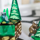 Detailaufnahme einer Eule auf einer grünen Magnetplatte, daneben ein Waschbär.