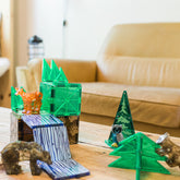 Spielsituation auf einem Holztisch mit aufgebauten Magnetstrukturen, Reh, Eule, Bär und Waschbär in Wohnzimmerumgebung