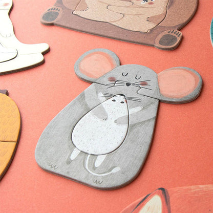 Puzzleteil in Form einer grauen Maus, die ihr kleines Mäusebaby im Arm hält, auf orangem Hintergrund.