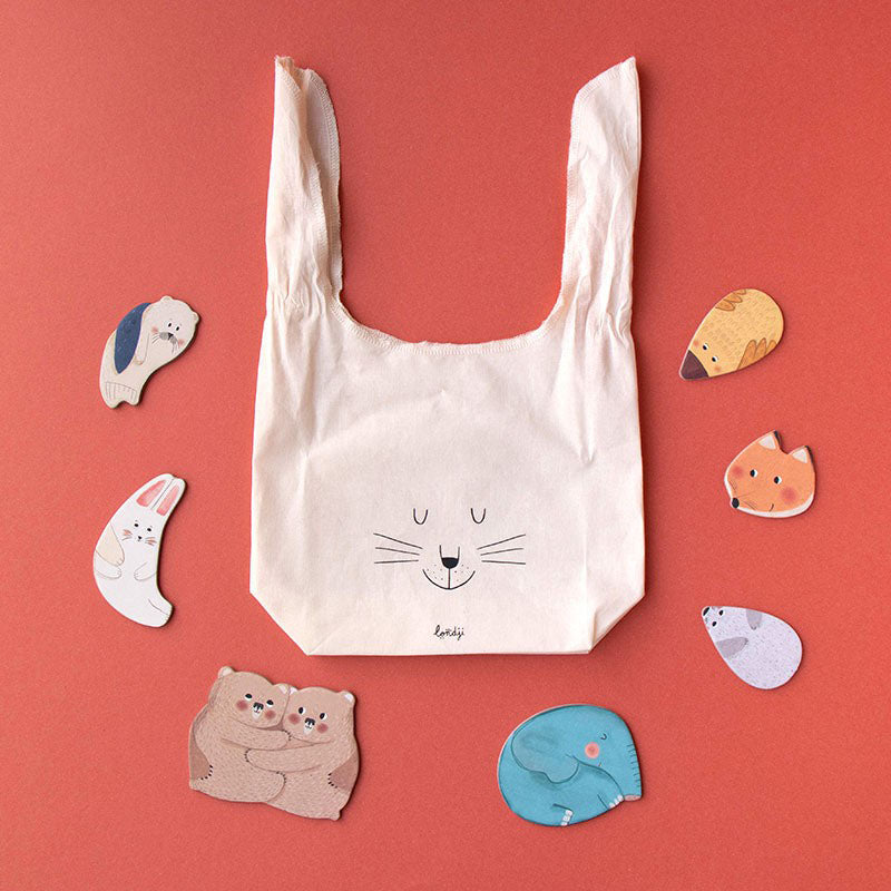 Stofftasche mit Hasengesicht, daneben einzelne Puzzleteile von Tiermüttern und ihren Jungen.