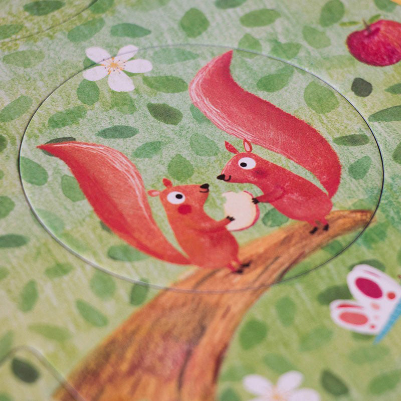 Detailansicht eines Puzzleteils mit zwei roten Eichhörnchen, die gemeinsam ein Stück Apfel halten, Hintergrund grüne Blätter.