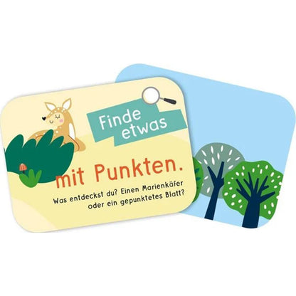 Spielkarten mit Illustrationen – Eine Karte zeigt einen Rehkopf hinter einem Busch mit der Aufgabe „Finde etwas mit Punkten“, die Rückseite ist mit stilisierten Bäumen bedruckt.