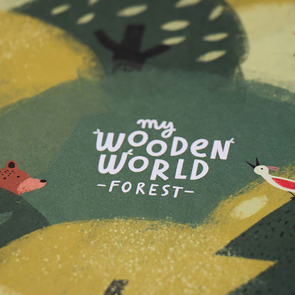 Detailaufnahme des Schriftzugs „My Wooden World – Forest“ auf grünem Hintergrund mit Waldbewohnern.