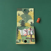Verpackung geöffnet, sichtbar mit bunter Waldlandschaft und einer Holzfigur daneben.