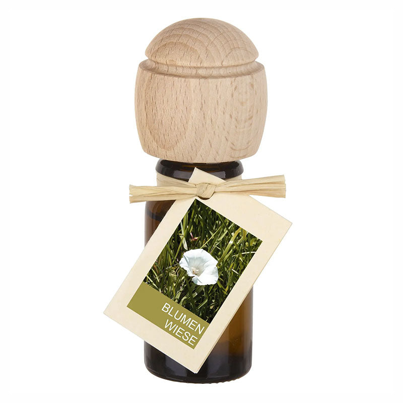 Raumduftflasche mit Holzaufsatz und Etikett Blumenwiese, zeigt eine weiße Blüte im Gras.