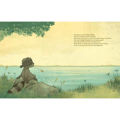 Buchseite: Waschbär sitzt entspannt auf einem Felsen am Seeufer unter einem Baum.