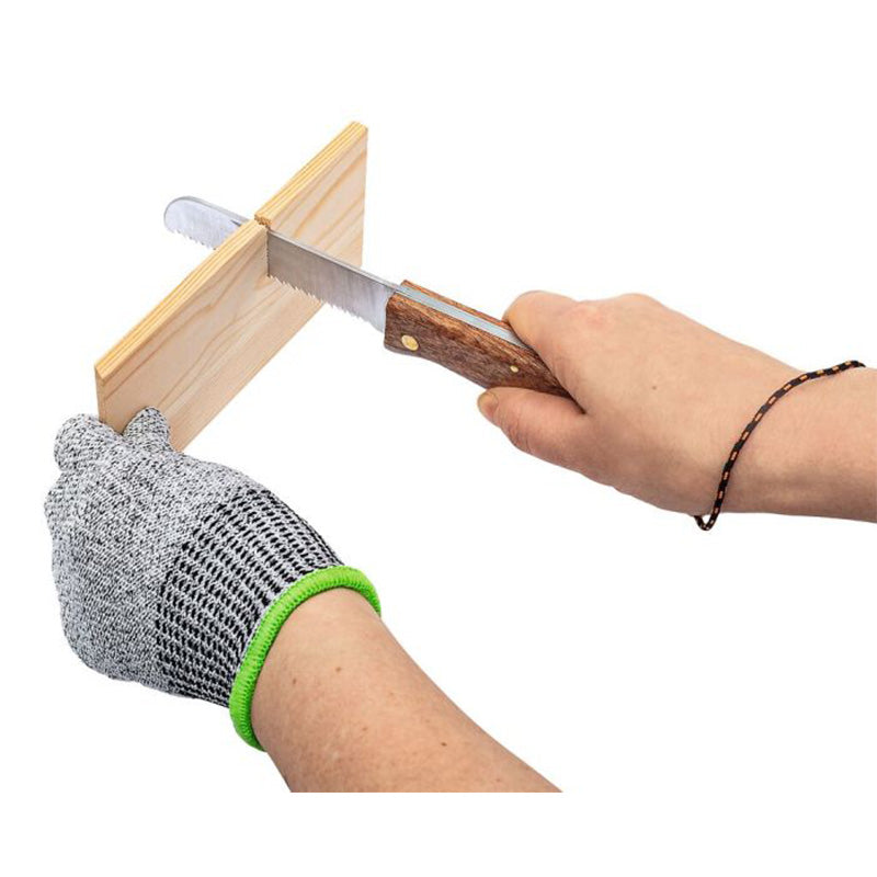 Person sägt ein Holzbrett mit einer Handsäge, während sie schnittfeste Handschuhe trägt.