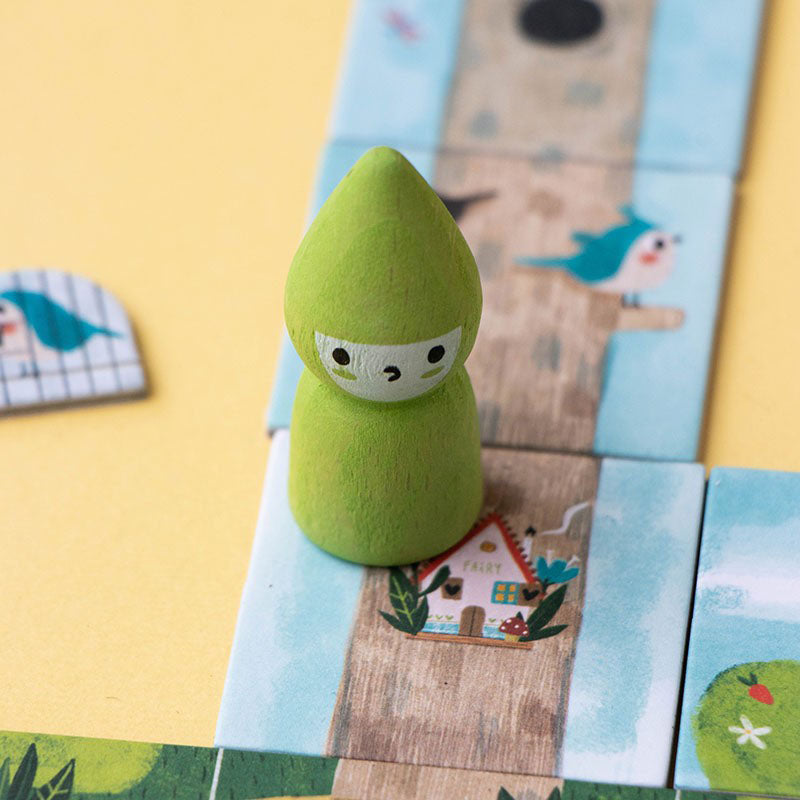 Nahaufnahme der grünen Spielfigur (Fee) auf einem Spielplättchen mit einem Feenhaus.