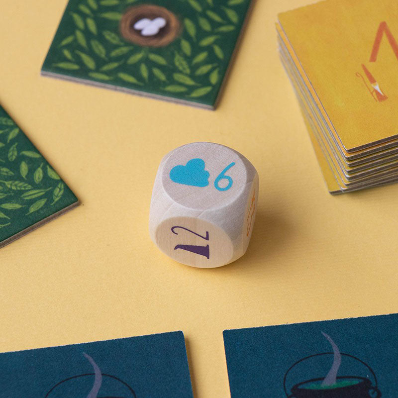 Holz-Würfel mit Symbolen und Zahlen auf Spieluntergrund.