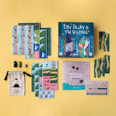 Komplettübersicht des Spielinhalts: Karten, Spielfiguren, Würfel, Anleitung und Schachtel auf gelbem Hintergrund.