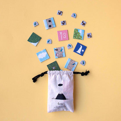 Stoffbeutel von Londji mit Spielplättchen, die herausfliegen, auf gelbem Hintergrund arrangiert.