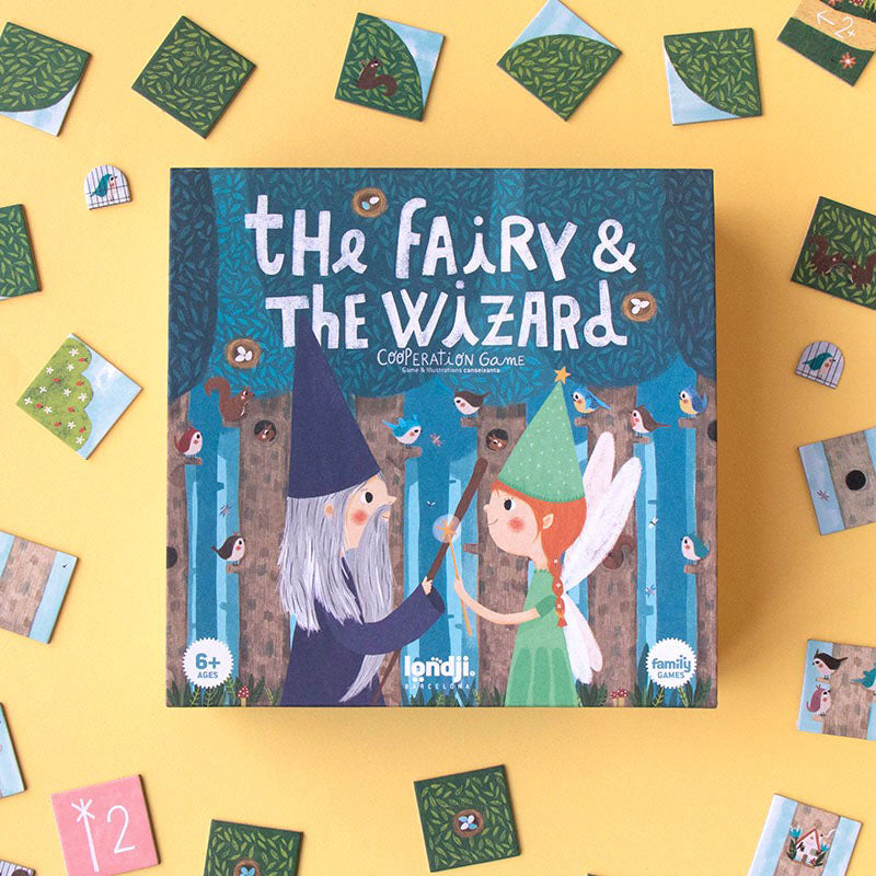 Spielbox „The Fairy &amp; The Wizard“ von Londji auf gelbem Hintergrund, umgeben von Spielplättchen