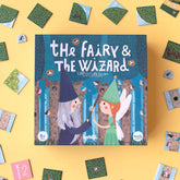 Spielbox „The Fairy & The Wizard“ von Londji auf gelbem Hintergrund, umgeben von Spielplättchen